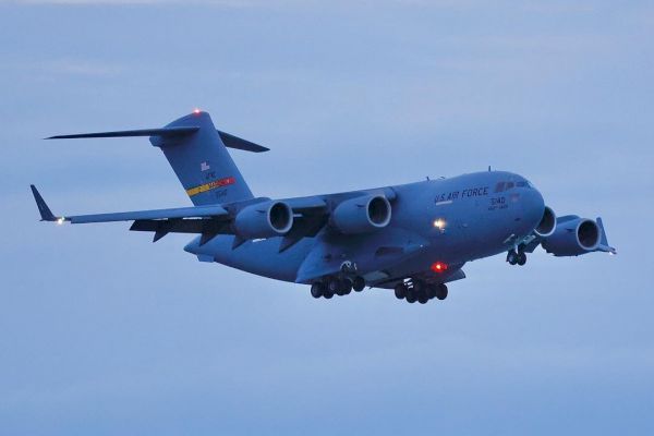 The image shows a military transport aircraft with the text 