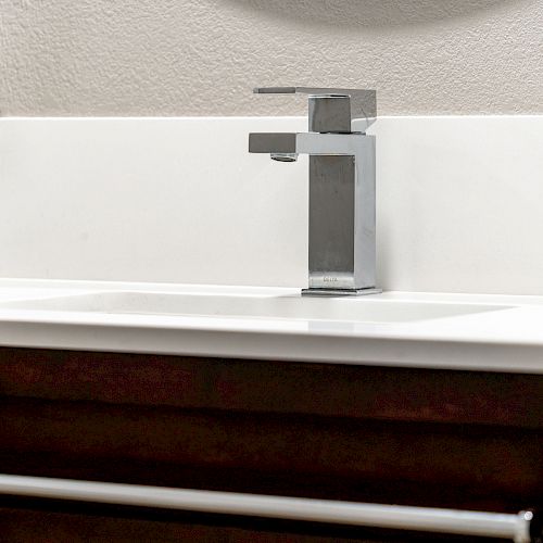 The image shows a modern bathroom sink with a sleek, minimalist faucet and a white countertop.